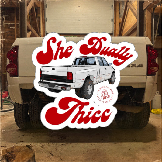 She Dually Thicc decal with a white dually pickup and red script, shown in front of a truck