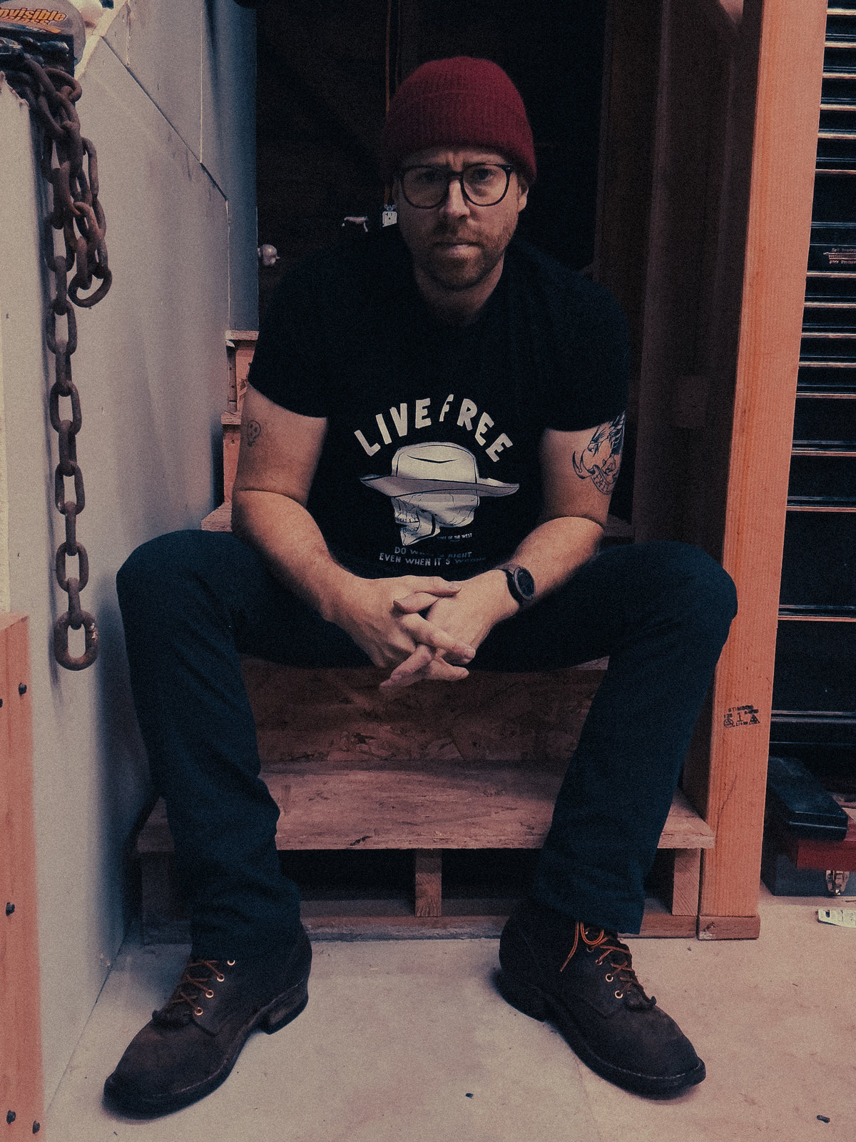 Person seated in a doorway wearing the black Do What’s Right graphic T-shirt