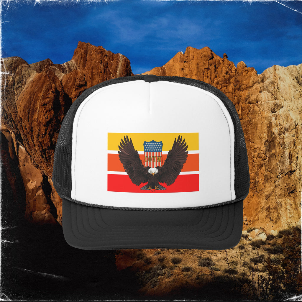 A black and white foam trucker hat with the image of a swooping eagle on it over the background of a rocky  canyon wall in Escalante Utah.