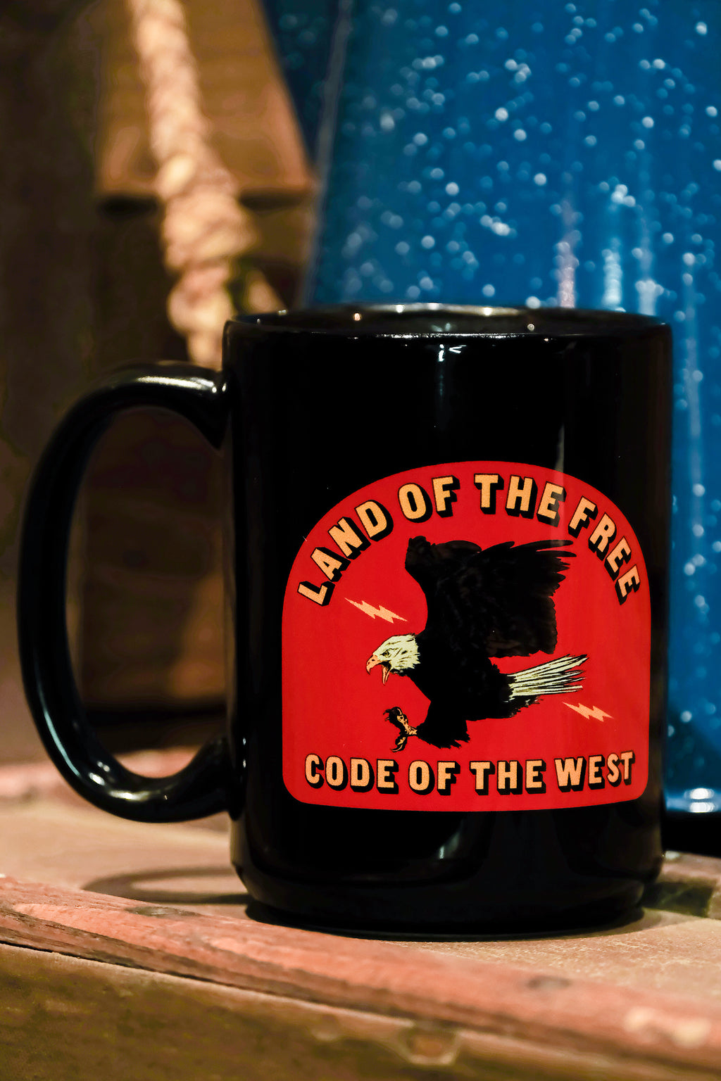 a black mug with a bright red logo showing a bald eagle swooping down with the words Land of The Free and Code of The West.